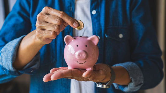 A man holds a coin in a pig-shaped piggy bank to save money for the future. 