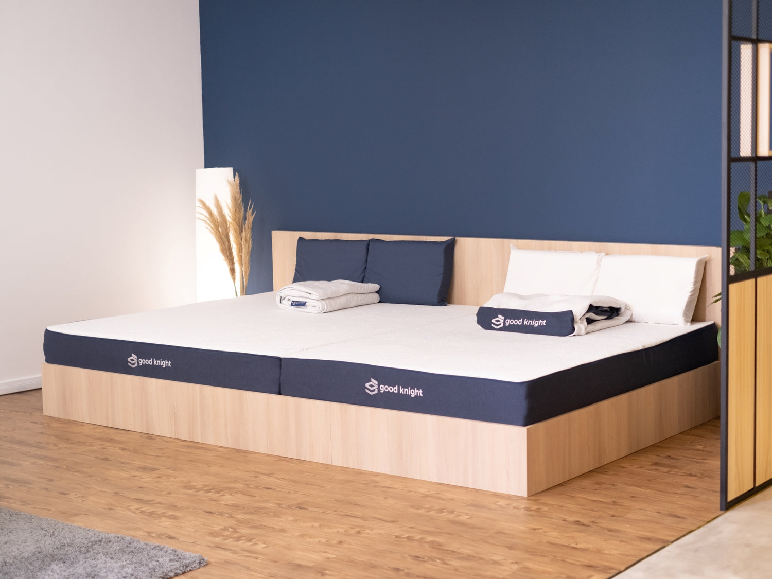 Good Knight showroom showcasing 2 Athena mattresses side by side on a big wooden bedframe with dark blue wall