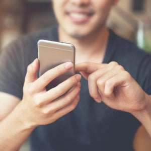 Happy male messaging using his smartphone in a modern coffee cafe