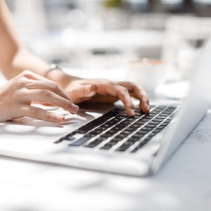 Hands of unrecognisable businesswoman typing on her laptop at cafe.